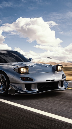 Silver Mazda RX-7 driving on a road