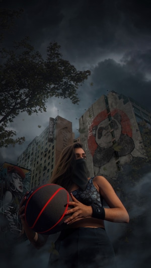 Girl holding a basketball in front of graffiti-covered buildings