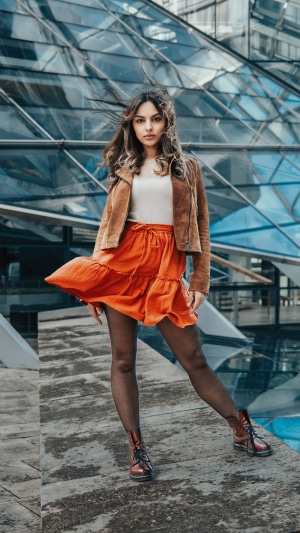 Model in orange skirt and brown jacket