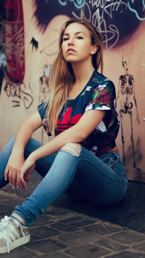 Model in Adidas shirt and ripped jeans
