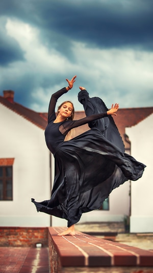 Ballerina in a black dress dancing outdoors