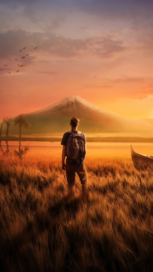 Man with backpack looking at mountain at sunset