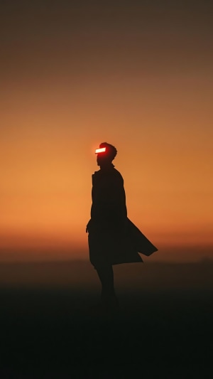 Silhouette of a person with glowing goggles at sunset