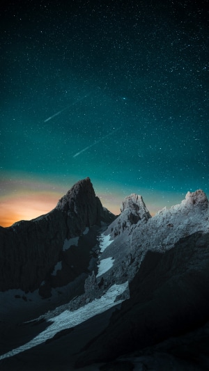 Mountains under a starry sky with shooting stars