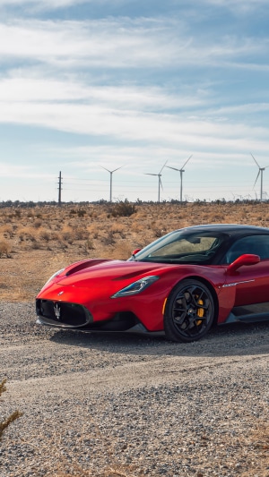 Red Maserati MC20 in a desert landscape with wind turbines
