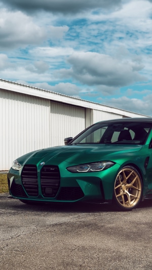 Green BMW M3 with gold wheels parked outside building