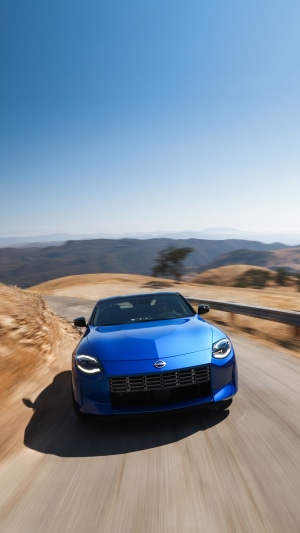 Blue 2023 Nissan Z driving on a mountain road
