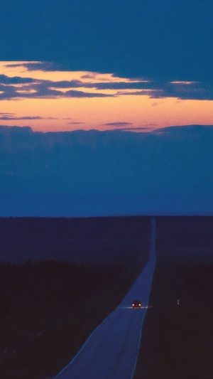 Car on a long road at dusk