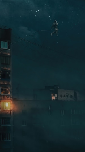 Man suspended by rope between buildings at night