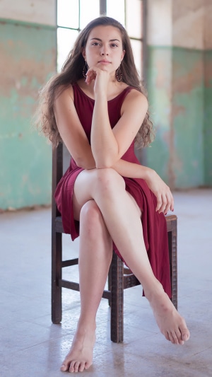 Young woman in a maroon dress sitting on a chair