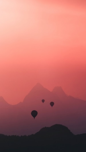 Hot air balloons over mountains at sunset