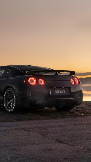 Black Nissan GT-R with custom license plate at sunset