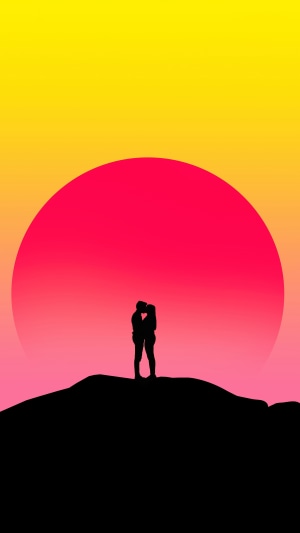 Couple kissing on a hill at sunset