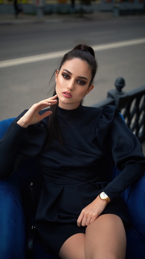 Woman in black dress sitting on blue chair