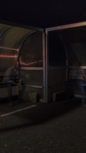People sitting at a bus stop at night