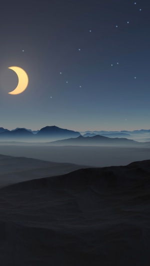 Crescent moon over misty mountains at night