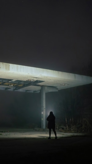 Person standing under a damaged overpass at night