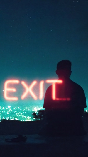 Silhouette with neon EXIT sign at night