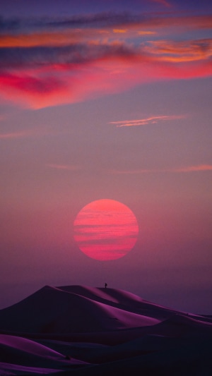 Desert dunes at sunset with a lone figure