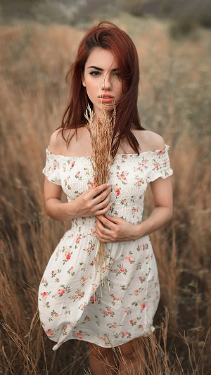 Woman with red hair in a floral dress in a field
