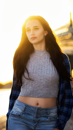 Young woman in crop top and jeans at sunset