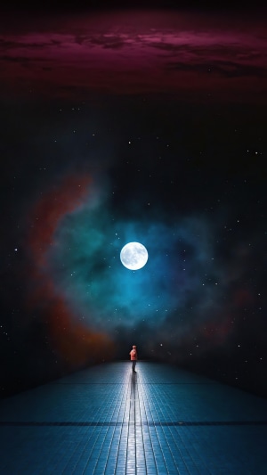 Person standing on a walkway looking at the moon and nebula