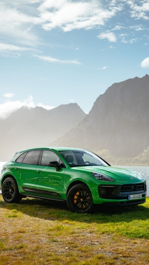 Green Porsche Macan parked on a grassy hill