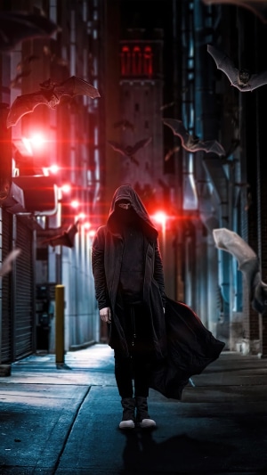 Person in a hooded cloak in a dark alley with bats