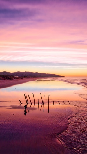 Sunrise over a beach with wooden posts