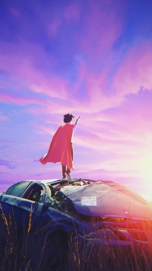 Boy in a cape on a wrecked car