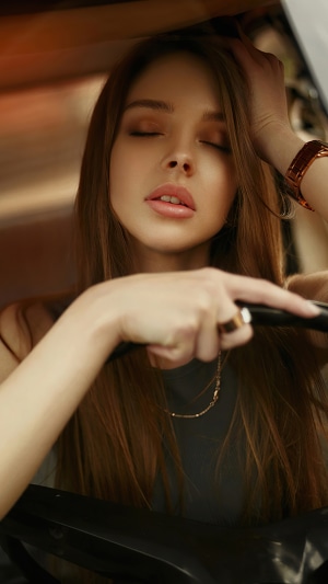 Woman with closed eyes holding steering wheel