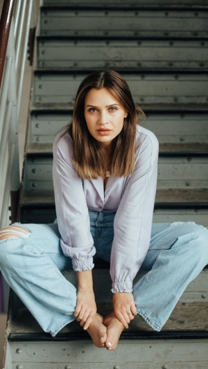 Model sitting on stairs in ripped jeans