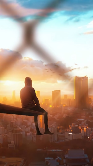 Person sitting on a beam overlooking city at sunset