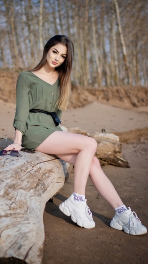 Young woman sitting on a log on a beach