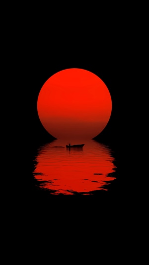 A lone boat on the water under a large red sun