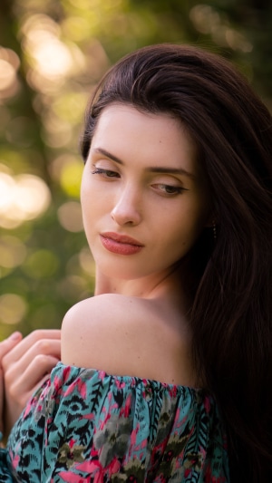 Model with dark hair wearing a floral off-the-shoulder top