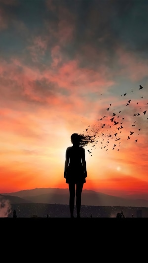Silhouette of a woman with birds flying from her head at sunset