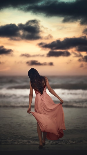 Woman in a dress on a beach at sunset