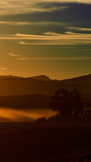 Misty mountains at sunrise with layered clouds