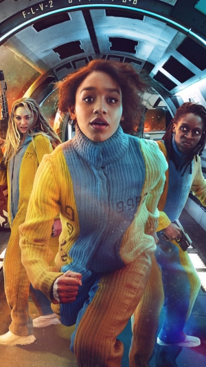 Three women in yellow and blue jumpsuits in a spaceship