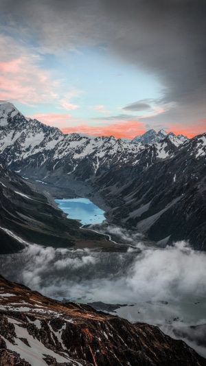 Snowy mountains overlooking a blue lake at sunset
