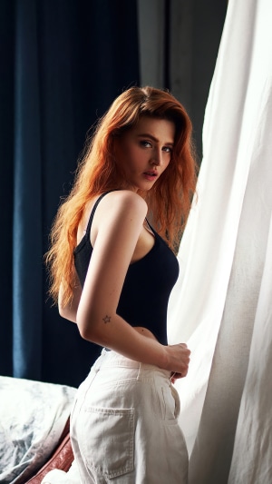 Redhead model in black top and white pants
