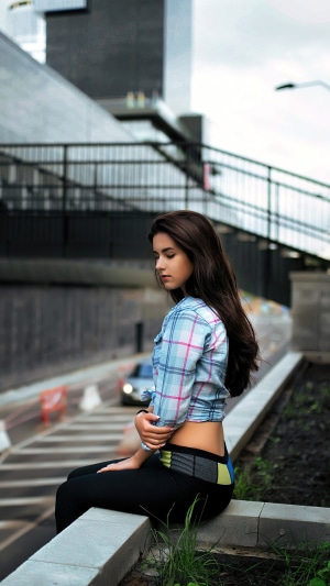 Girl in plaid shirt sitting outdoors