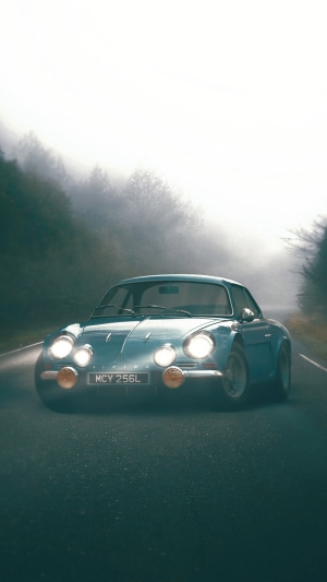 Blue Alpine A110 driving on a foggy road