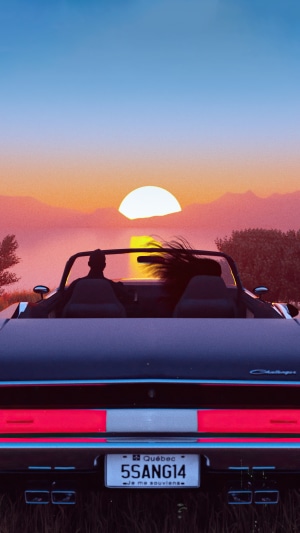 Couple in convertible driving at sunset