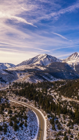 Snowy mountains and winding road under a cloudy sky