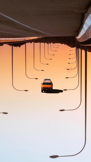 Orange car under a bridge with streetlights