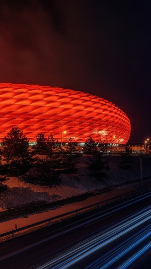 Allianz Arena stadium illuminated in red at night with light trails