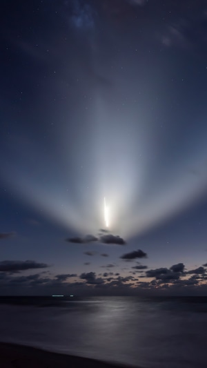 SpaceX rocket launch over ocean at night