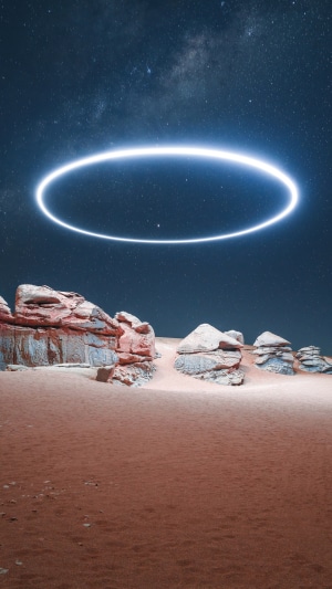 Glowing ring in starry sky over desert rocks